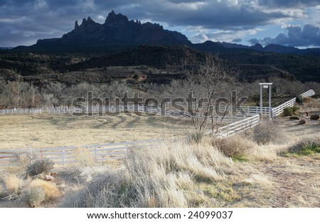 This is an image of a ranch entrance in Utah near Zion Canyon as the sun paints the entrance but the background mountains are shaded by passing storm clouds.
