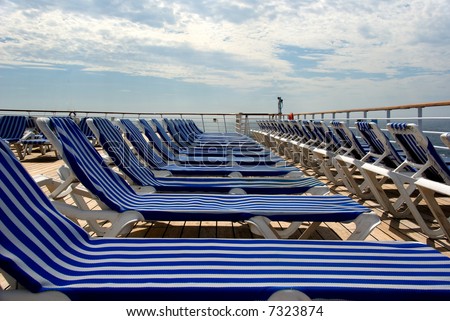 Lounge chairs in a row on upper deck of cruise ship.