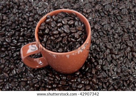 Coffee mug full of coffee beans on pile of coffee beans