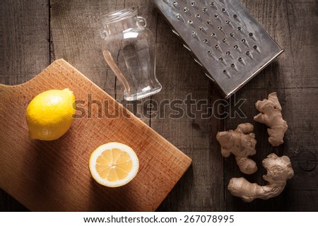 Ginger, lemon, grater and jar on table