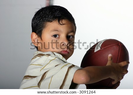 Cute Hispanic boy holding a football ready to throw