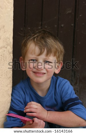 young caucasian boy sitting outside pretending to read a brochure