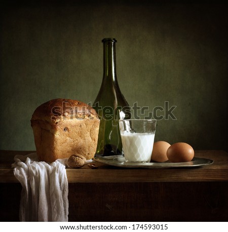 Still life with fresh bread, milk, eggs and a bottle of wine