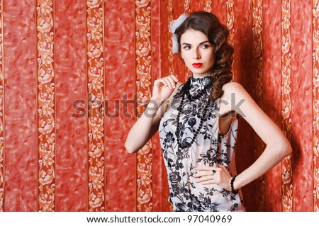 Beautiful girl with curly hair standing in the corner on red wallpaper background