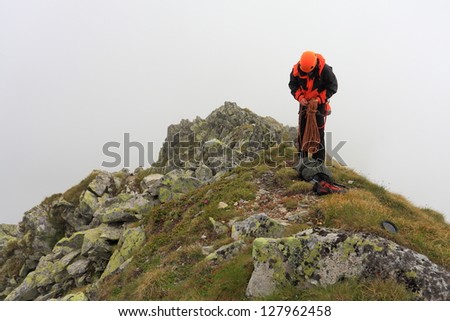 Man coiling the rope and preparing for descent after rock climbing