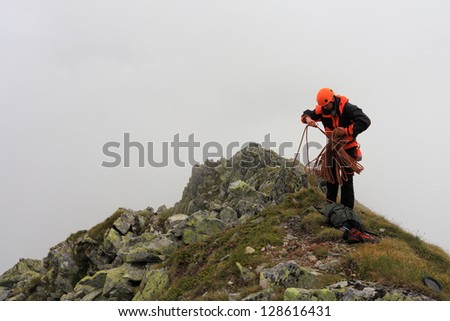 Mountaineer coiling the rope and preparing for descent after rock climbing