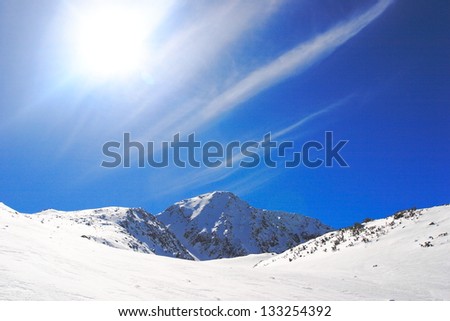 Mountains covered with snow under blue sky and shining sun in the winter