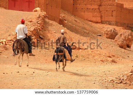 Two men riding donkeys in the desert, Morocco