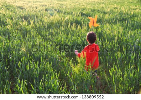 Kid playing on a green field under the sunset light