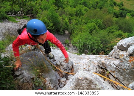 Woman climbing on the rock route, high above ground