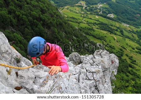 Girl climbing on limestone rocks high above ground