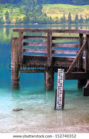 Water height measure tool near the wood pier on clear mountain lake