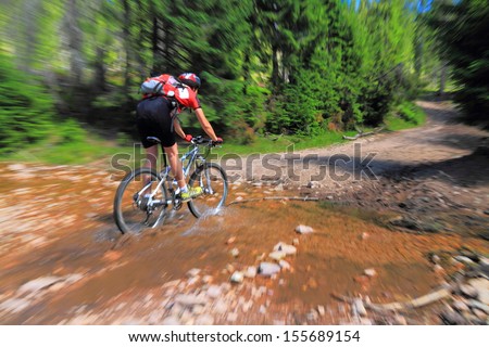 Mountain biker crosses a water stream on the mountain