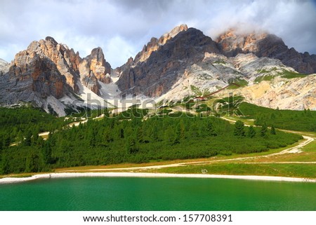 Green mountain lake and distant mountains, Dolomite Alps, Italy