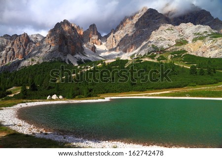 Green mountain lake and distant mountains, Dolomite Alps, Italy