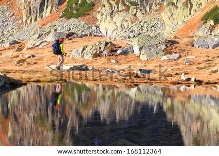 Tourists and mountains near glacier lake reflected by calm waters