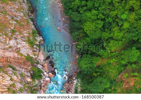 Blue water and green vegetation at the bottom of a deep canyon