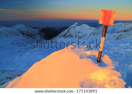 Snow covered mountain summit illuminated by the setting sun