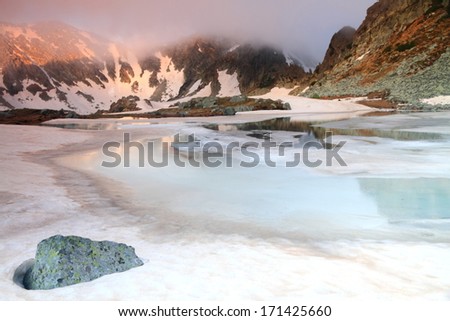 Early morning on the mountains with ice and snow melting on glacier lake