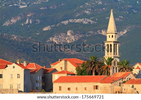 White church tower and old venetian buildings near the Mediterranean sea at sunset
