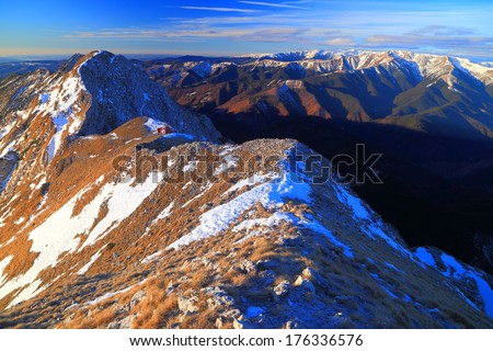 Curved mountain ridge covered with snow patches at sunrise