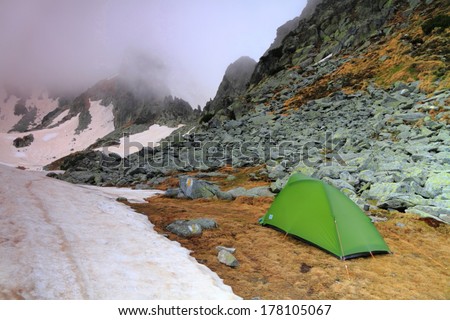 Camping site and green tent on the mountain in cloudy weather