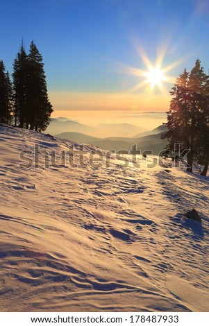 Sun setting beyond horizon on snow covered mountain