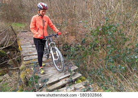 Mountain biker crosses a narrow bridge