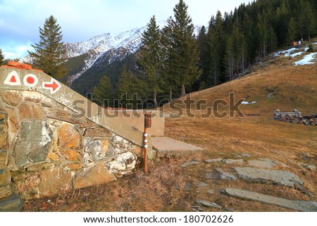 Stone stairs of an old hut with trail signs and distant mountains