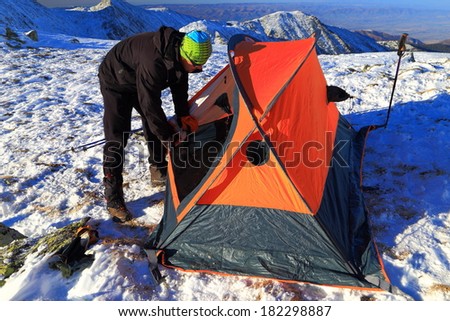 Climber works around the tent on a mountain camp