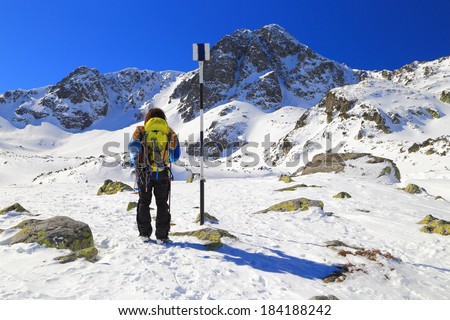 Mountaineer climbs a mountain covered with snow in sunny winter day