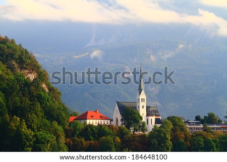 White clouds above tall church in the Alps