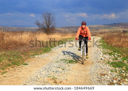 Sunny road in the country side and woman on a bike trip