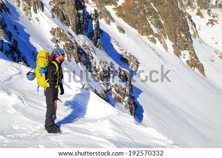 Mountaineer standing on a snow ledge in sunny day