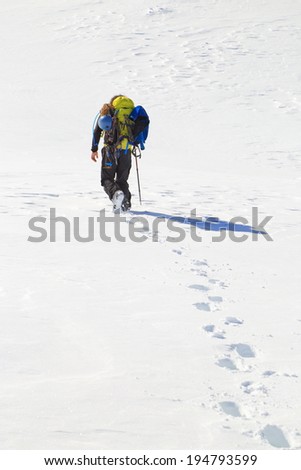 Distant mountaineer and foot steps on the snow