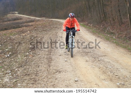 Woman rides a bike on a dirt road in overcast day