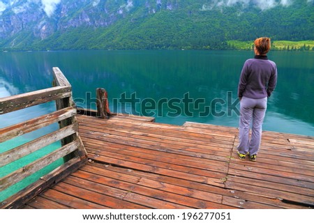 Single woman waiting for a boat on wet wood pier