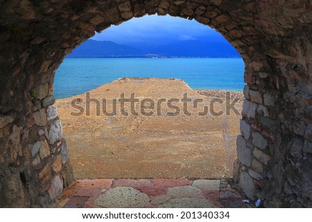 Small pier seen from inside arched gate to the Mediterranean sea, Greece