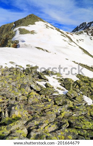 Sunny mountain landscape with summits spotted with snow under blue sky
