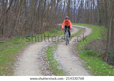 Woman cycling a winding forest road on a mountain bike