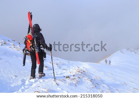 Mountaineer carries skies and gear attached to the backpack