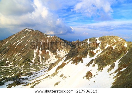 Spring day on the mountains with snow melting on deep valley