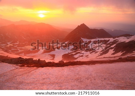 Red sun and sky above snow covered  mountain at sunset