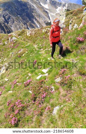 Young hiker trail surrounded by pink mountain flowers on a narrow trail