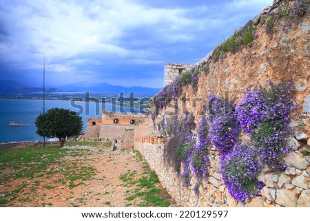 Cloudy sky above the blue flowers and walls of the Palamidi Castle, Nafplio, Greece