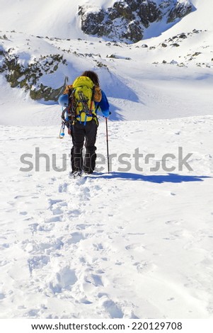 Mountaineer walking foot steps trail on snow covered mountain