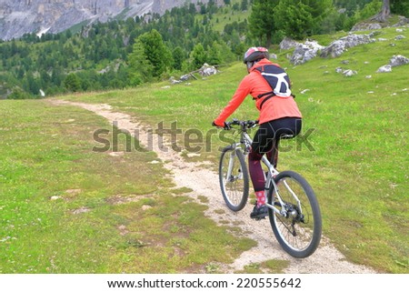 Woman riding a bike on the mountain road near Sella pass, Dolomites Alps, Italy