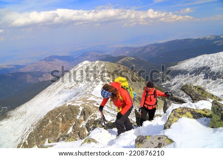 Climbers ascending snow covered mountain summit in sunny day