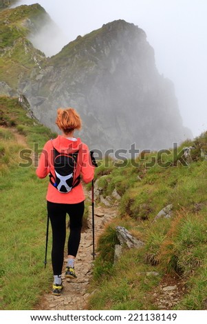 Mountain trail and woman hiker covered by clouds