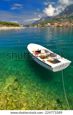 Clean waters of Adriatic sea and white boat tied to the shore, Makarska, Croatia